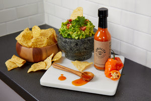 Lomalita habanero hot sauce bottle with habanero peppers with guacamole and tortilla chips